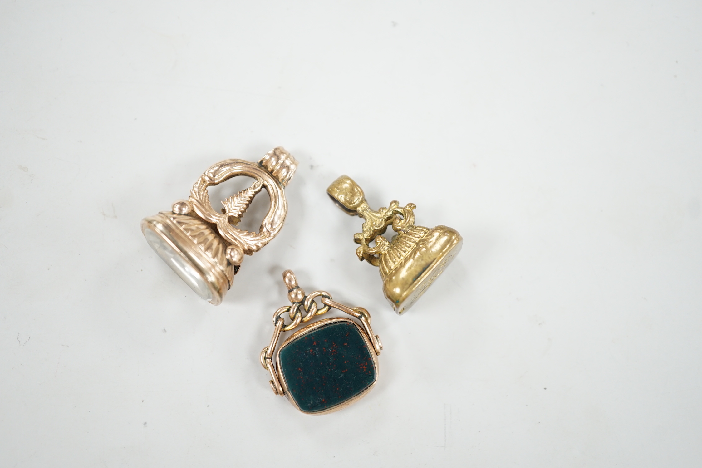 An Edwardian 9ct gold and bloodstone set spinning fob seal, 29mm and two other fob seals including yellow metal overlaid.